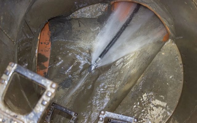 High-pressure jetting nozzle cutting through tree roots inside a sewer pipe